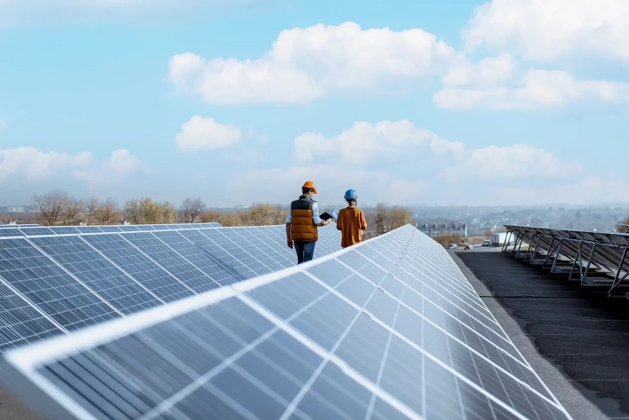 Zwei Personen inspizieren Solarmodule auf einem Dach für die Normec Zertifizierung.
